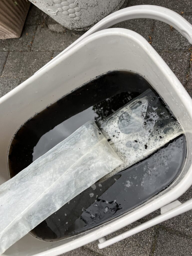 カビだけでなく、大量のホコリと強いヤニ汚れによって墨汁のような色にヘドロのような固形物の入ったエアコンクリーニングの汚水