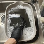 分解したレンジフードのファンを専用の洗剤が入ったバケツの中でつけ置き
