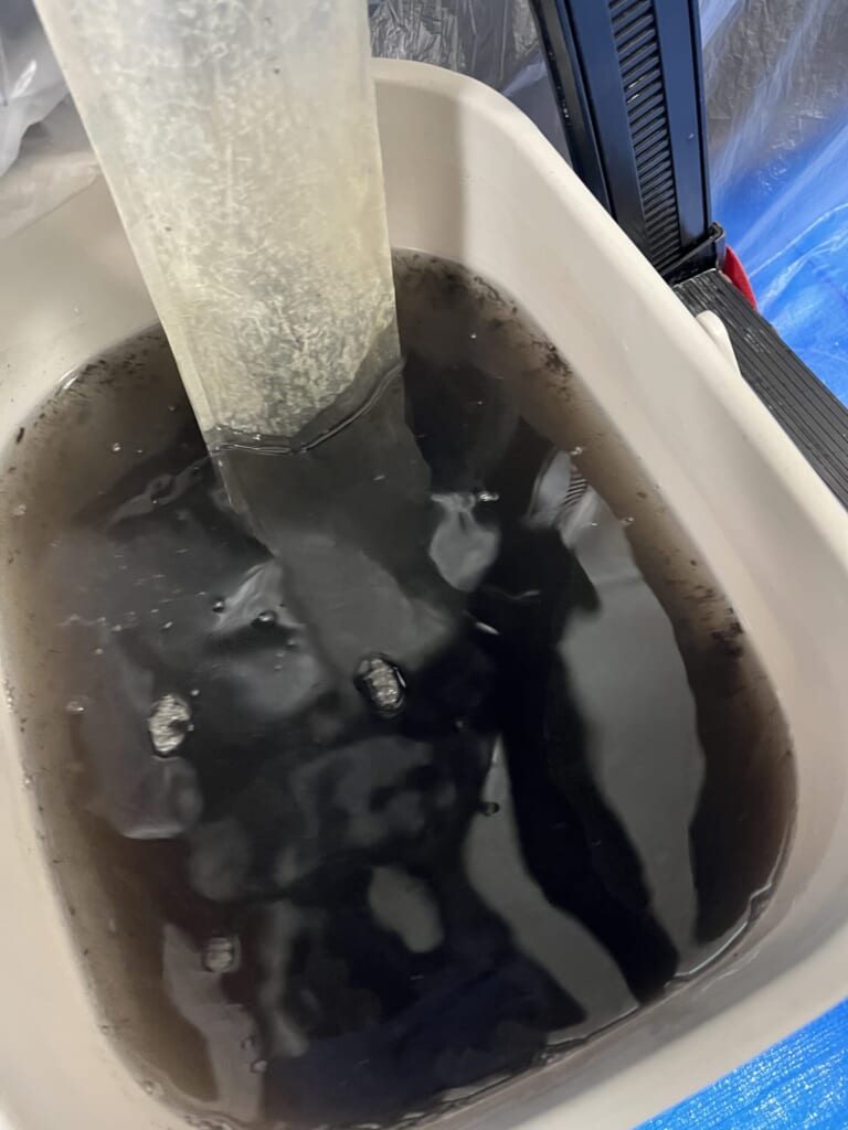 2年間使用したエアコンのクリーニング後の、油とカビの混ざった真っ黒な汚水
